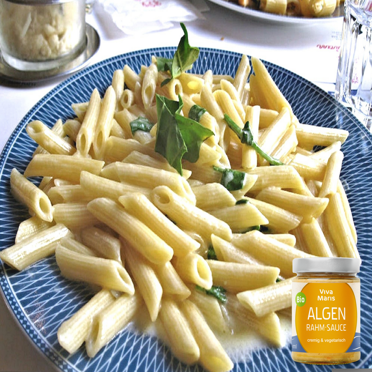Bio Algen Rahm-Sauce im Glas neben einem Teller mit Penne und Algen Rahm Sauce