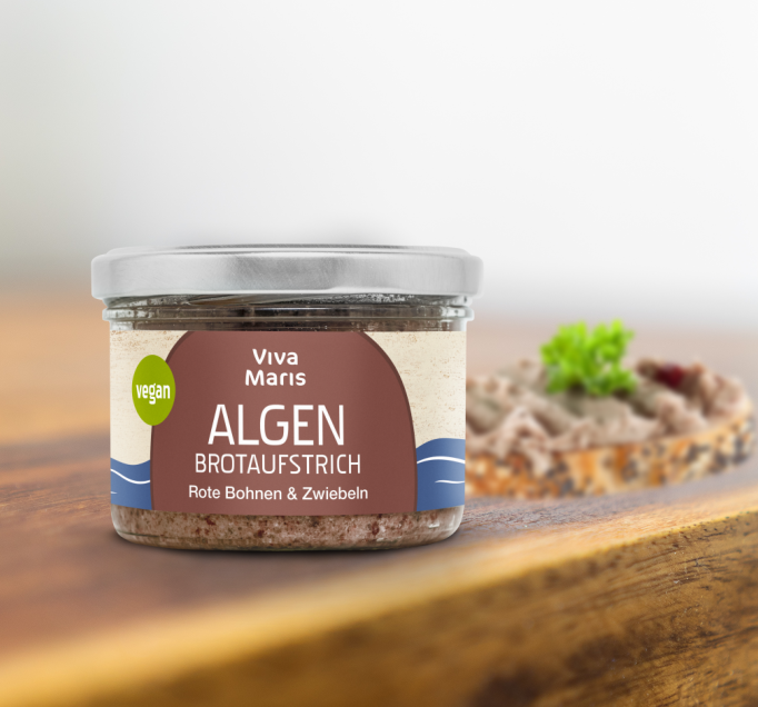 GENIESSER SET - Viva Maris ALGEN Brotaufstrich Rote Bohne & Zwiebel im Glas auf einem Tisch vor einem geschmiertem Brot mit dem Aufstrich