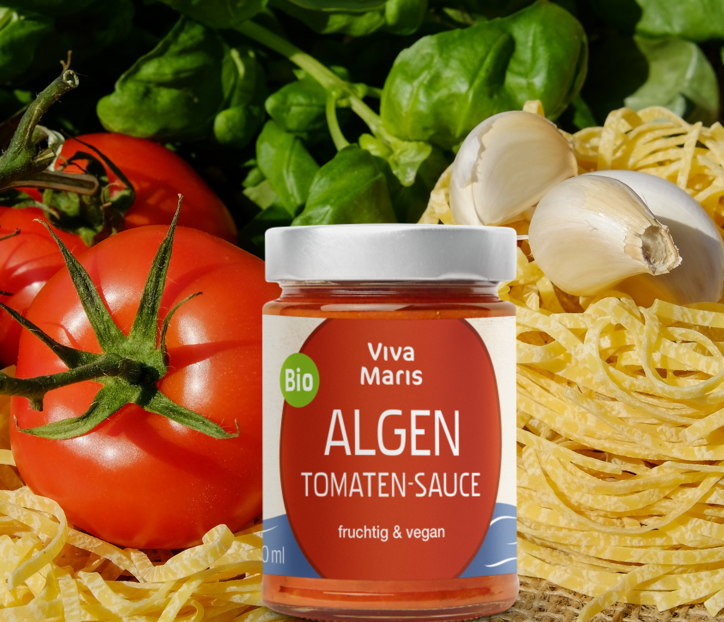 Bio Algen Tomaten-Sauce im Glas vor Tomaten und Pasta und Knoblauch