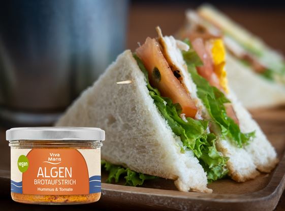 Viva Maris ALGEN Brotaufstrich Hummus & Tomate im Glas vor einem Sandwich mit Salat, Tomate und Hummus