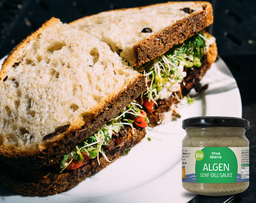 Viva Maris ALGEN Bio Senf-Dill Sauce im Glas neben einem Sandwich mit Kresse und Honig Senf Sauce